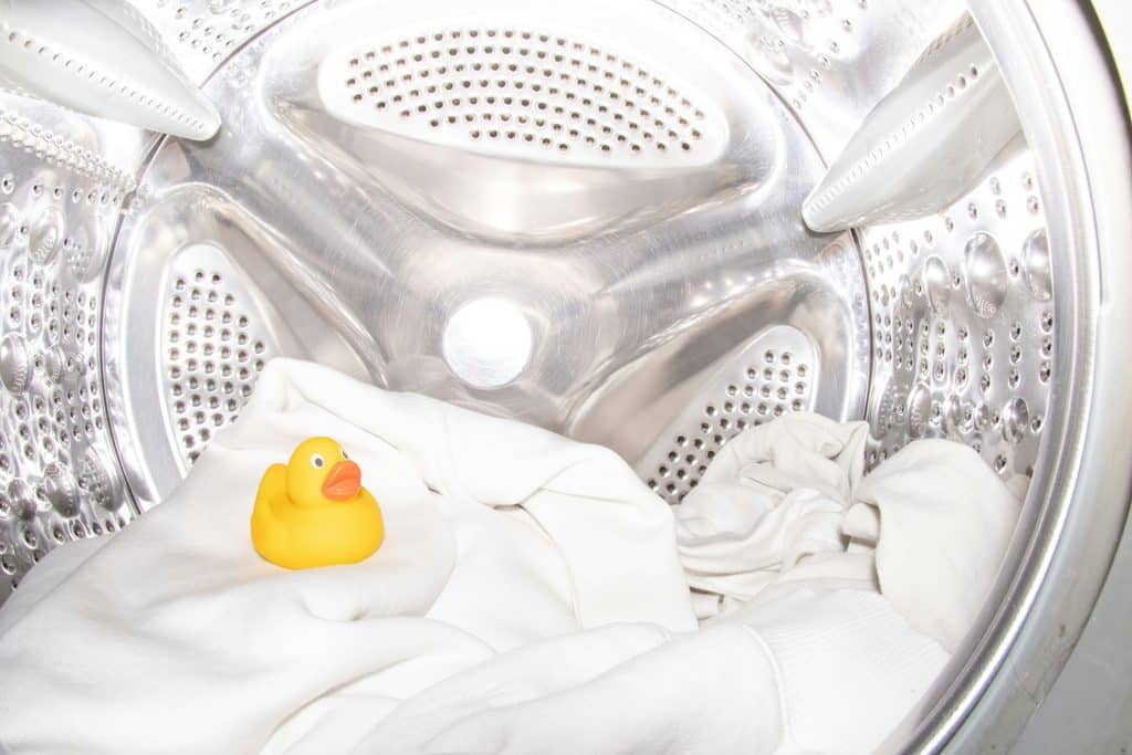 Person washing bedding to reduce dust mite allergens